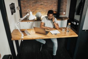 Man sitting at his desk, working from home while on the phone.
