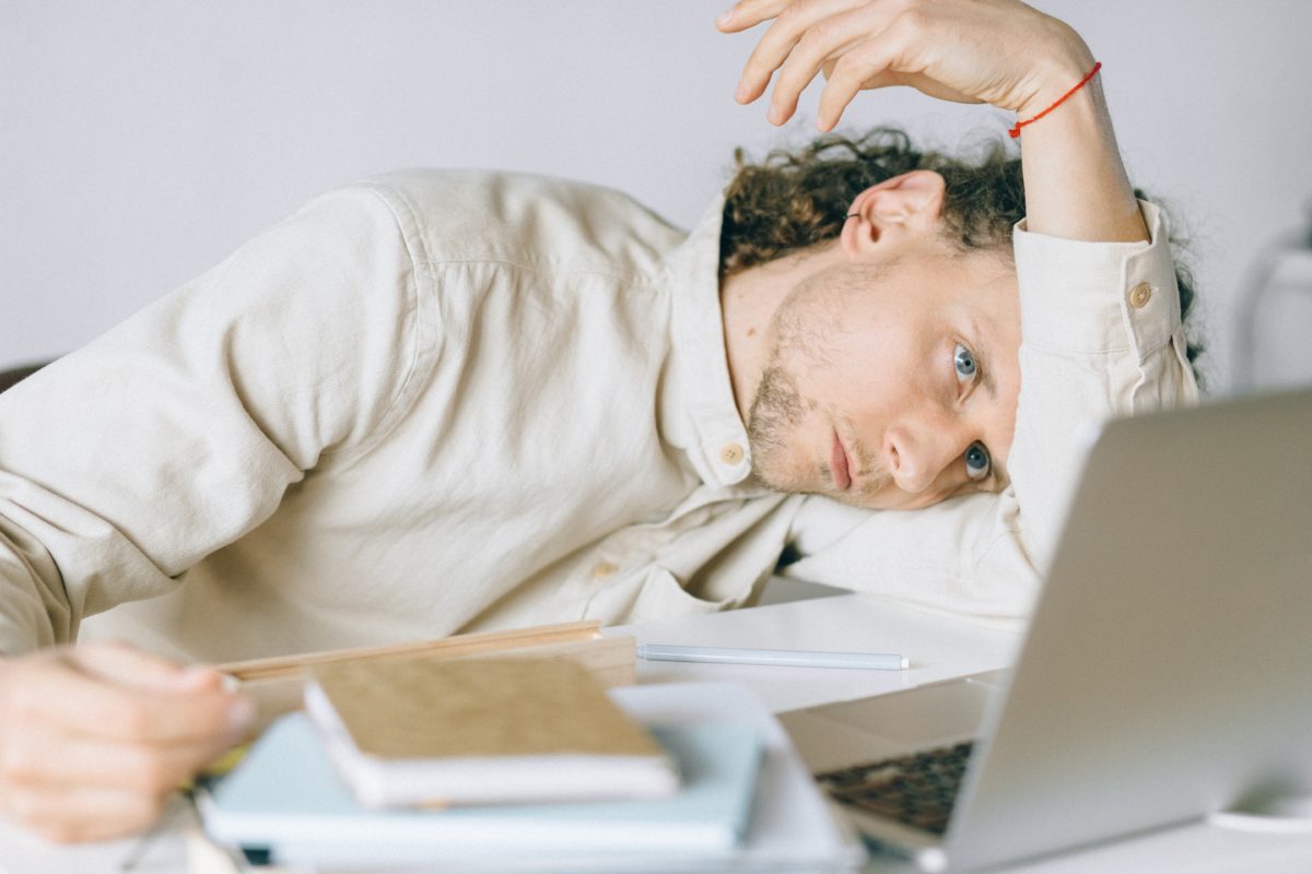 Young man laying his head on his desk. He looks tired